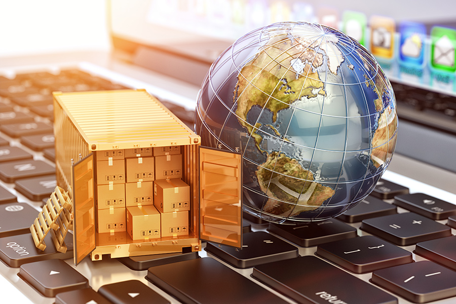 A globe and gold shipment container sit on top of a laptop keyboard