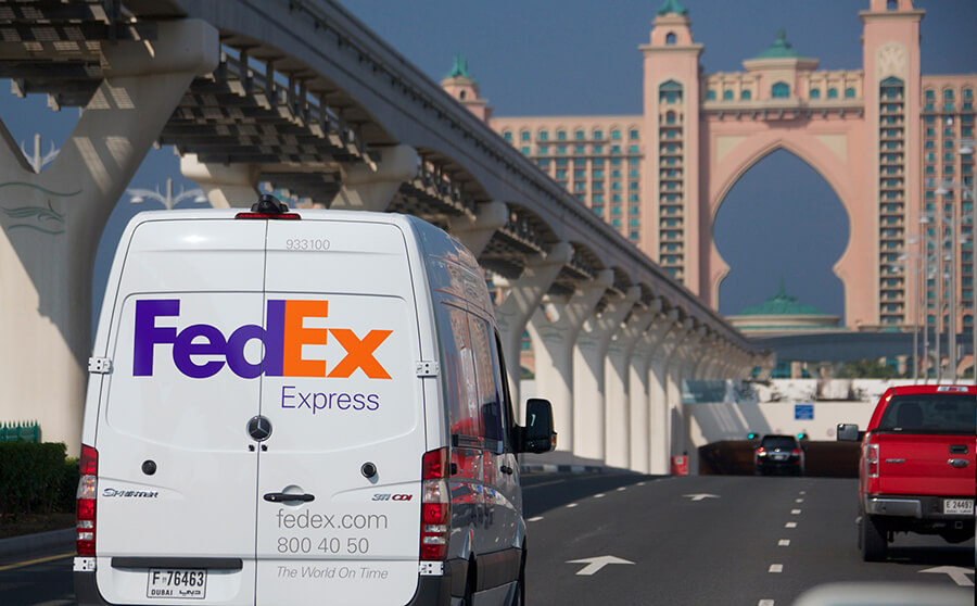 A FedEx delivery van drives down a road