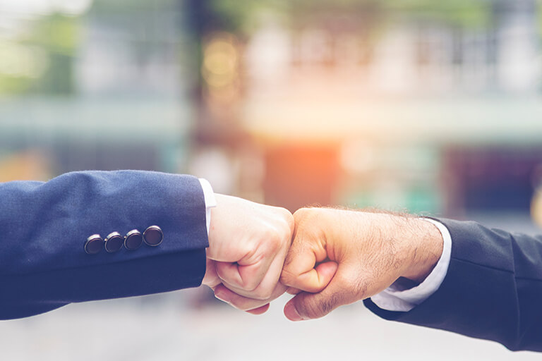 Two businessmen in suits fist bump
