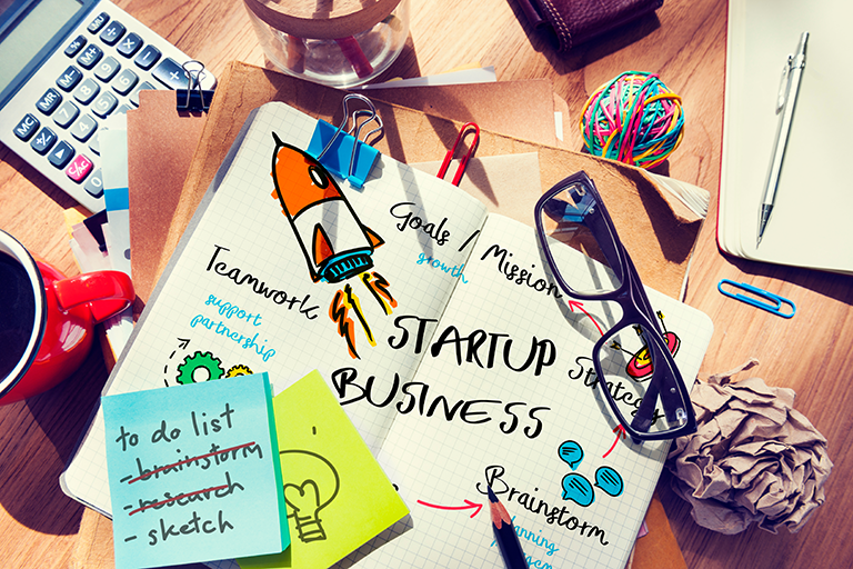notebook on desk reads startup business