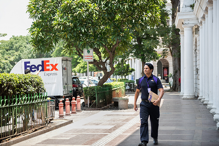 Indian male FedEx courier carries parcel on street