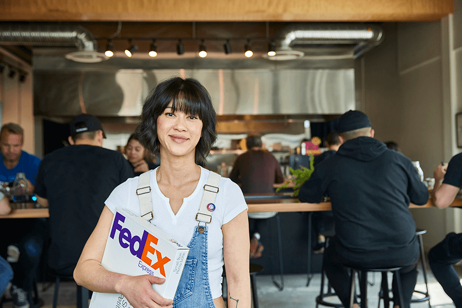Female business owner in dungarees holding FedEx package