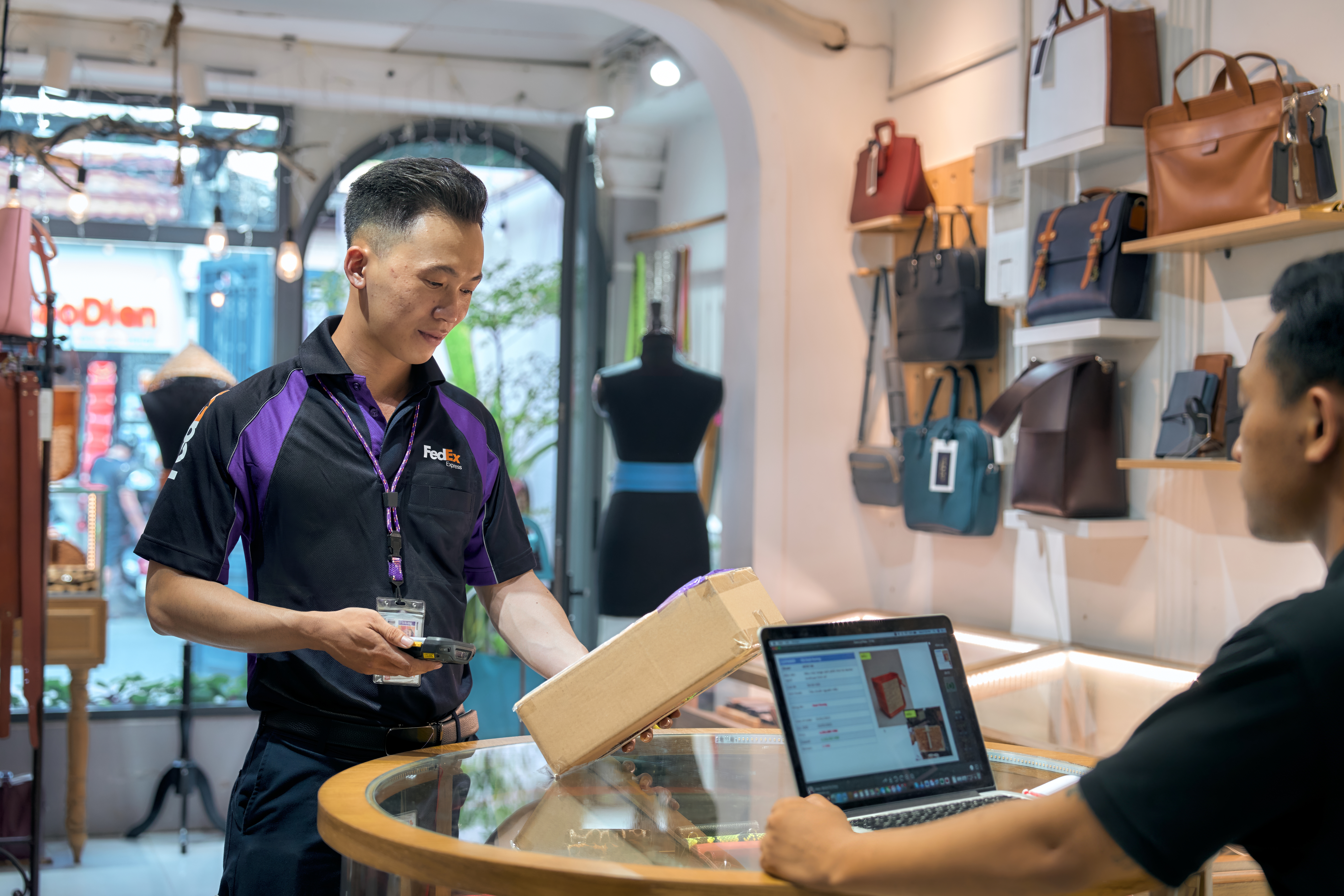 Male Vietnamese FedEx courier picking up parcel in retail store
