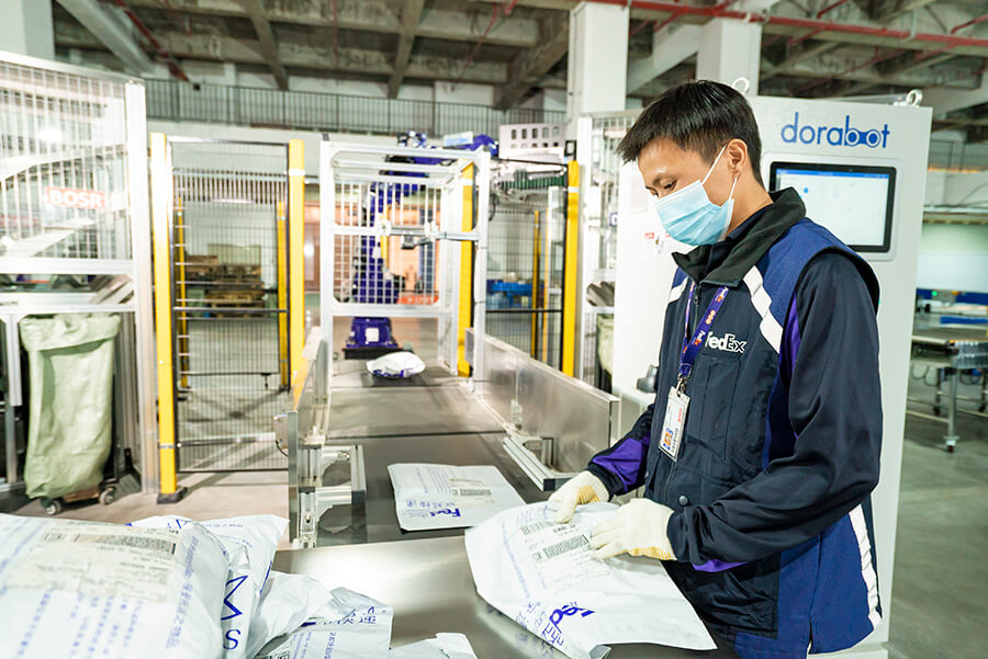 Male Chinese FedEx employee labels white packages in warehouse