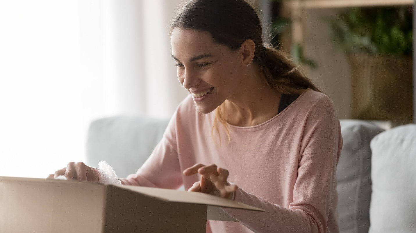 White woman smiles while opening a package