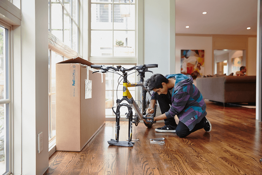 Man assembling a bicycle near large window