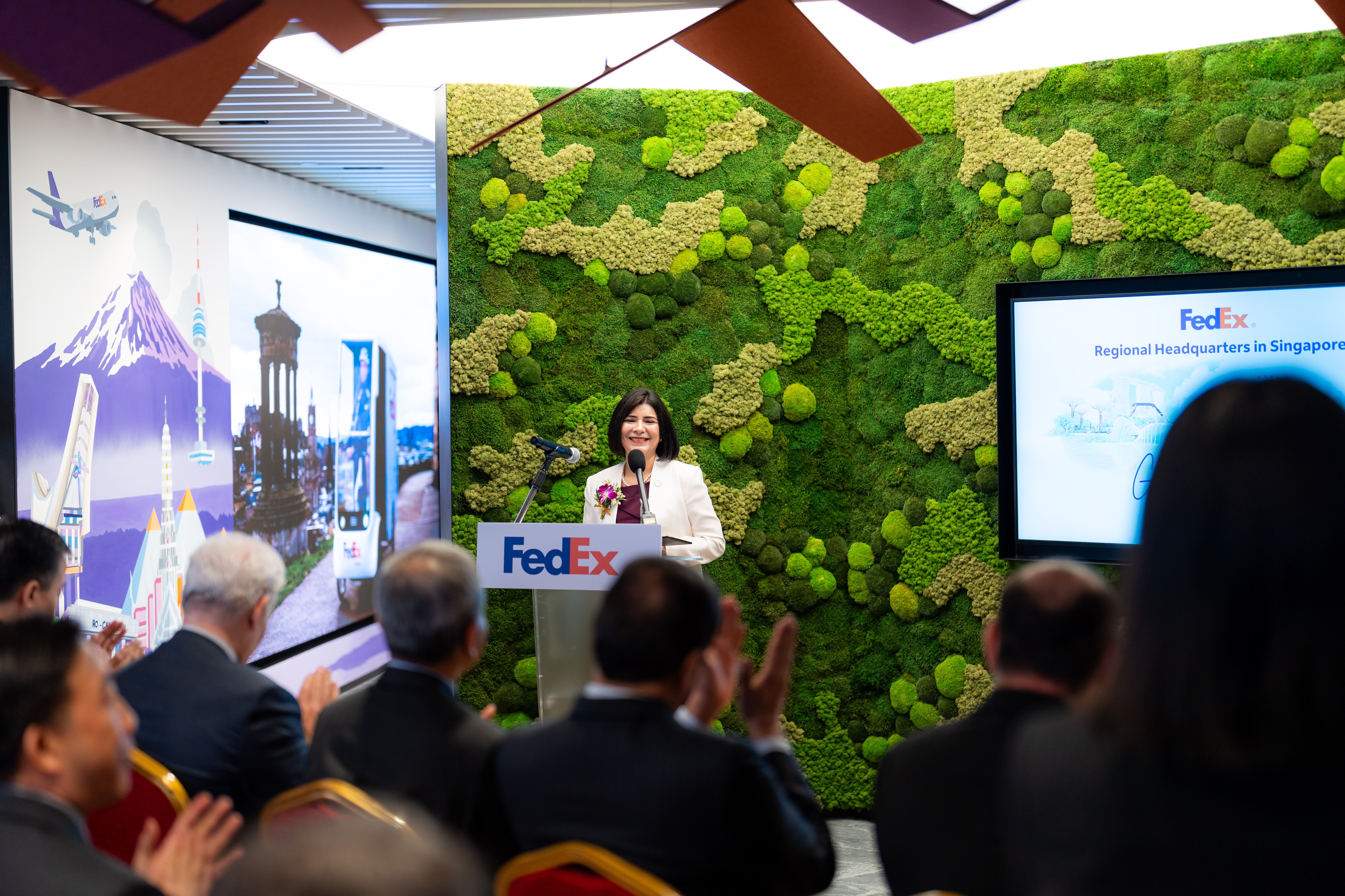 FedEx APAC president Kawal Preet speaking at the grand opening of the FedEx APAC headquarters in Singapore, in front of a green wall