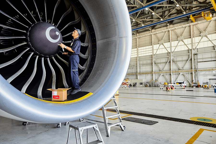 Engineers stands inside jetplane engine making repairs
