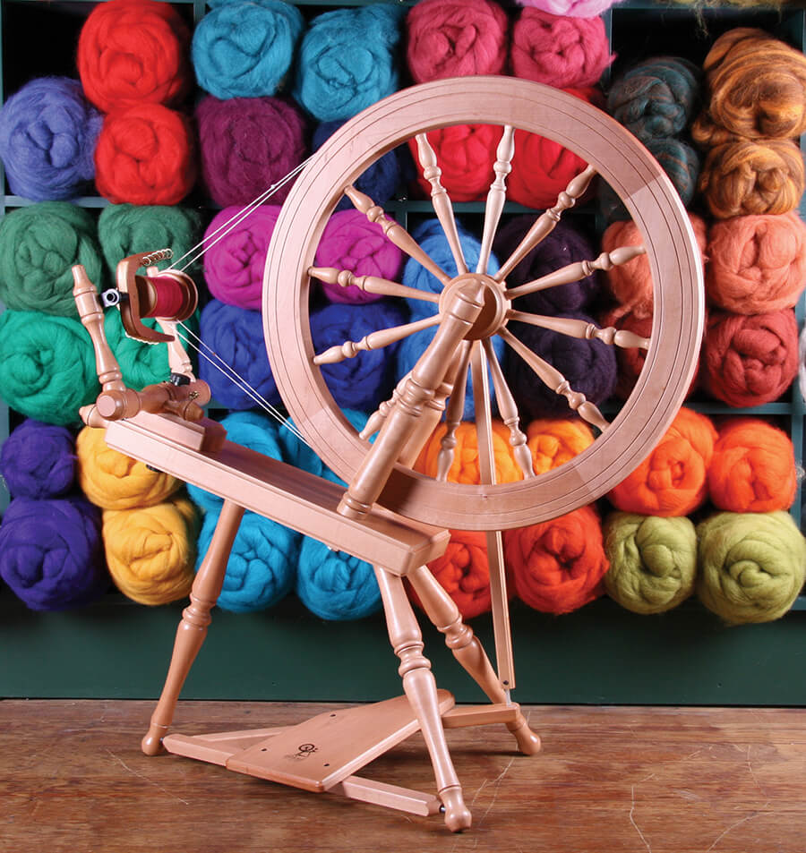 Spinning wheel and bright multi-coloured rolls of weaving loom