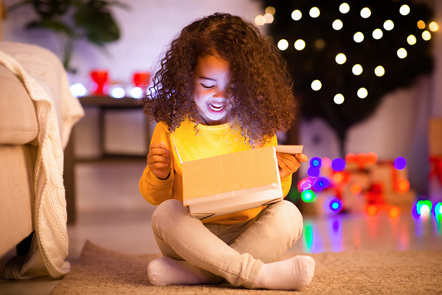 Young girl with curly hair opens festive gift