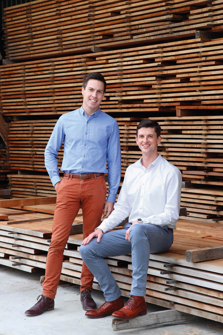 One man standing up and one sitting down in warehouse on wooden pallets
