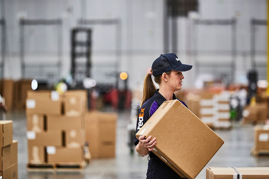 European female FedEx worker moves box in warehouse facility