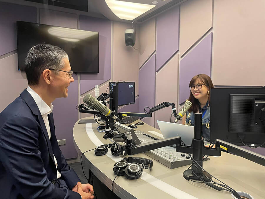 Female presenter interviews male in business suit in radio studio