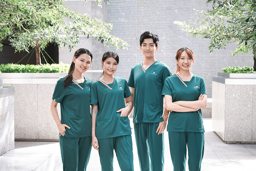 Four young Chinese male and female healthcare staff in green uniforms outdoors