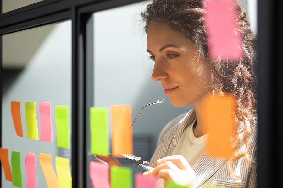 Female in workplace reviews post it notes on screen