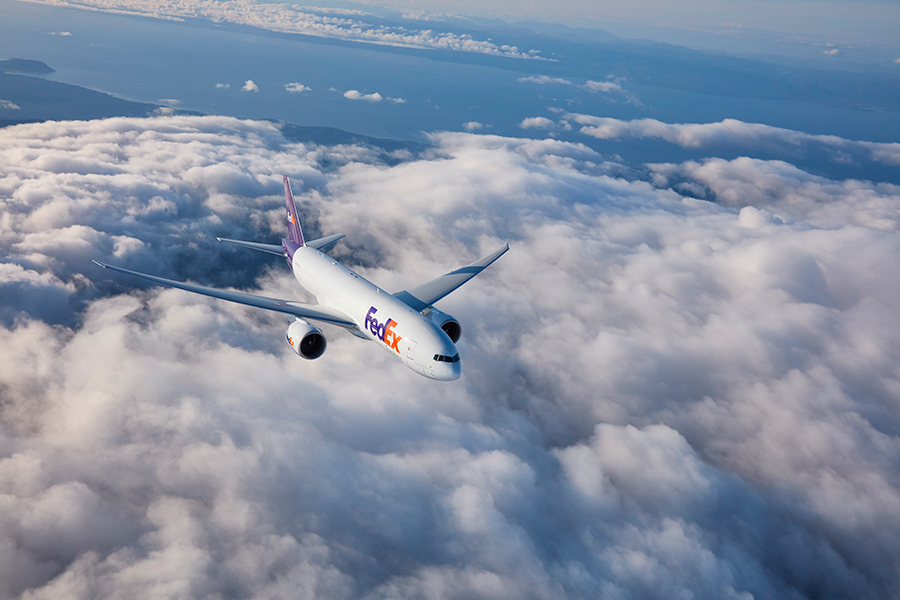 FedEx plane flying above clouds