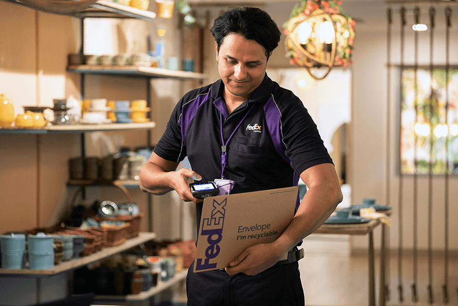 Male Indian FedEx courier scans FedEx parcel in retail shop