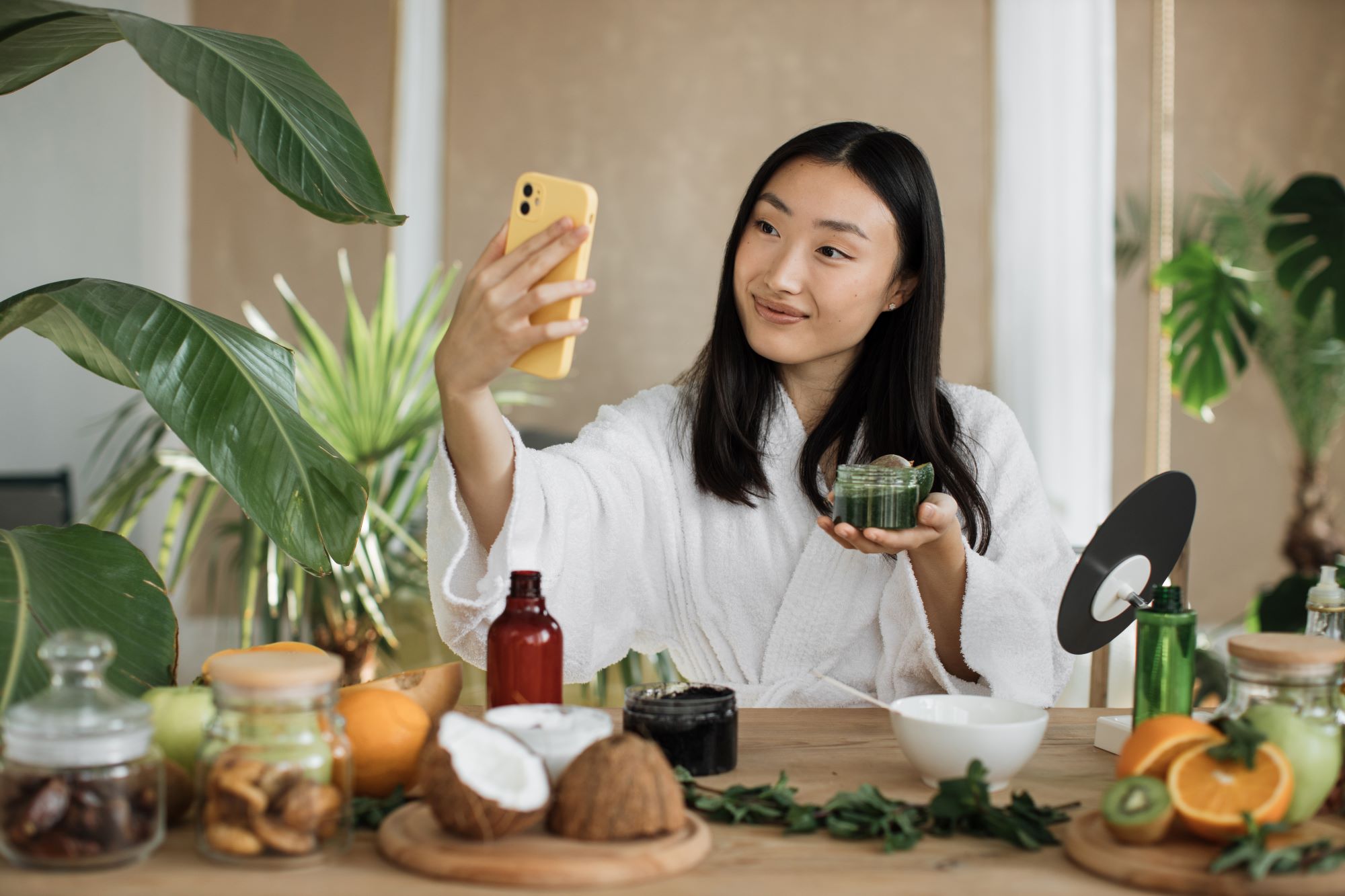 South Asian female taking selfie with beauty product in hand