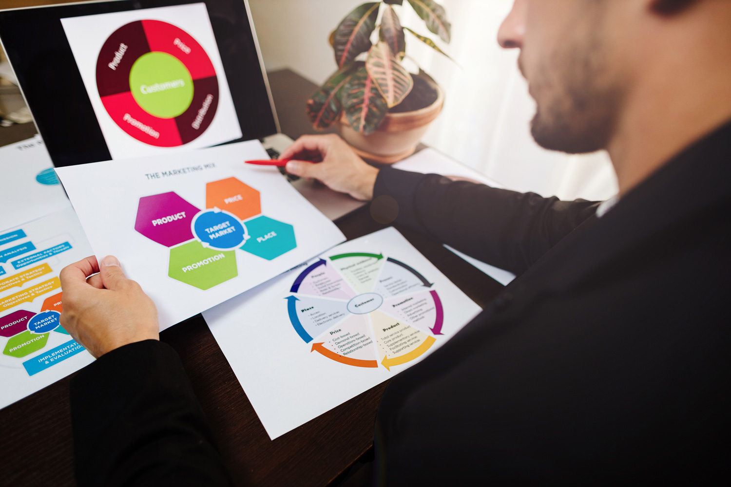 A man looks at a diagram on his laptop, with printouts of additional diagrams on his desk