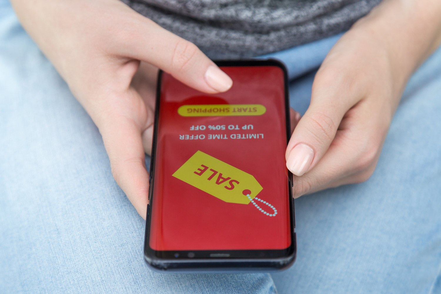 A person holds a smartphone displaying a “sale” tag and a limited-time offer message