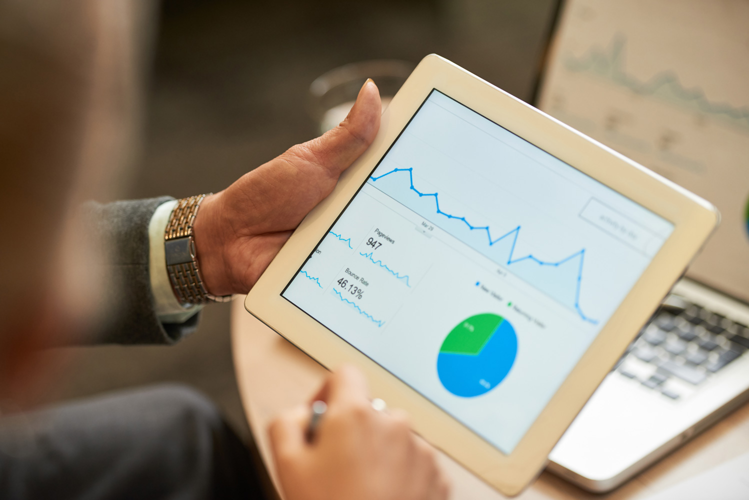 A person views data and charts via a tablet while making notes