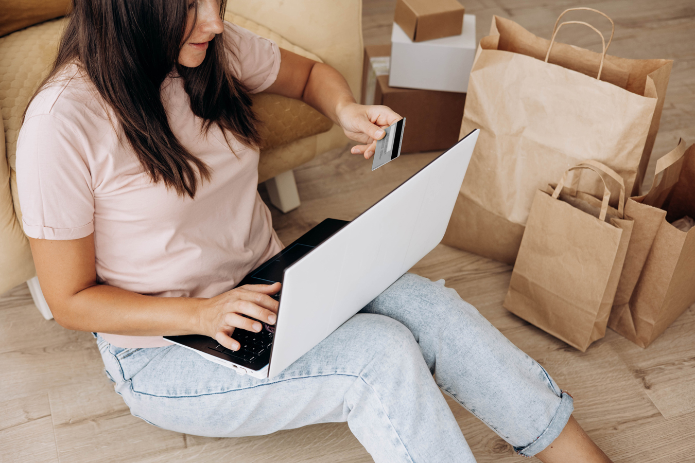 A woman at home, holding a credit card while shopping online on a laptop