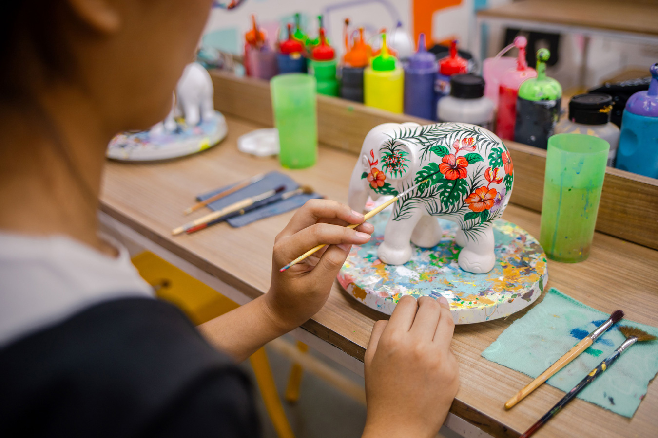 Thai female artist painting an elephant sculpture