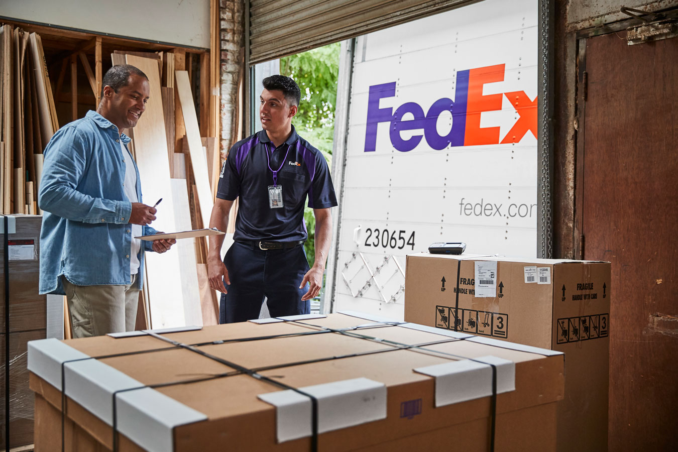 Male FedEx courier collects large shipment of oversize boxes from customer