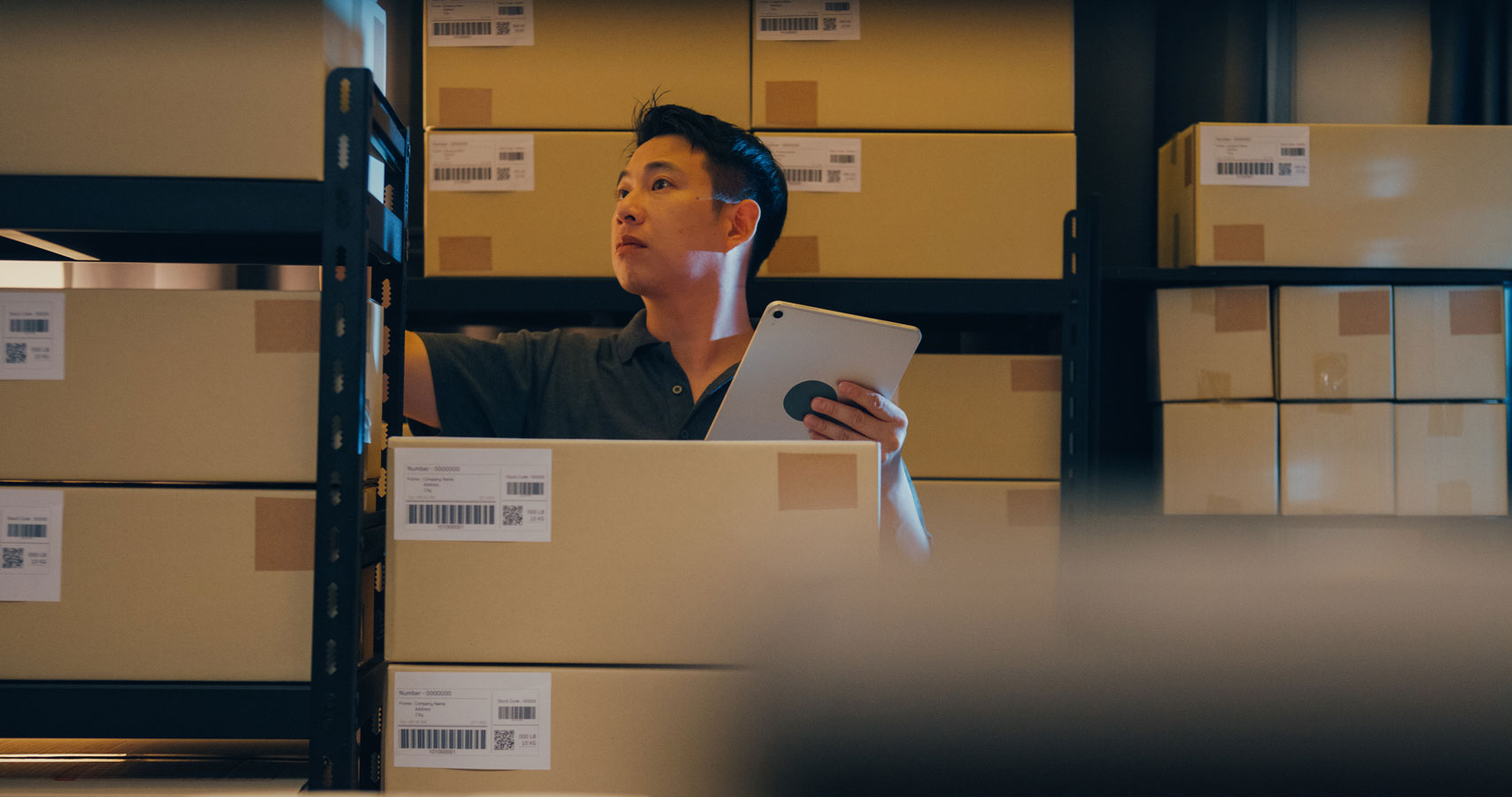 Asian male warehouse worker scan boxes on shelf