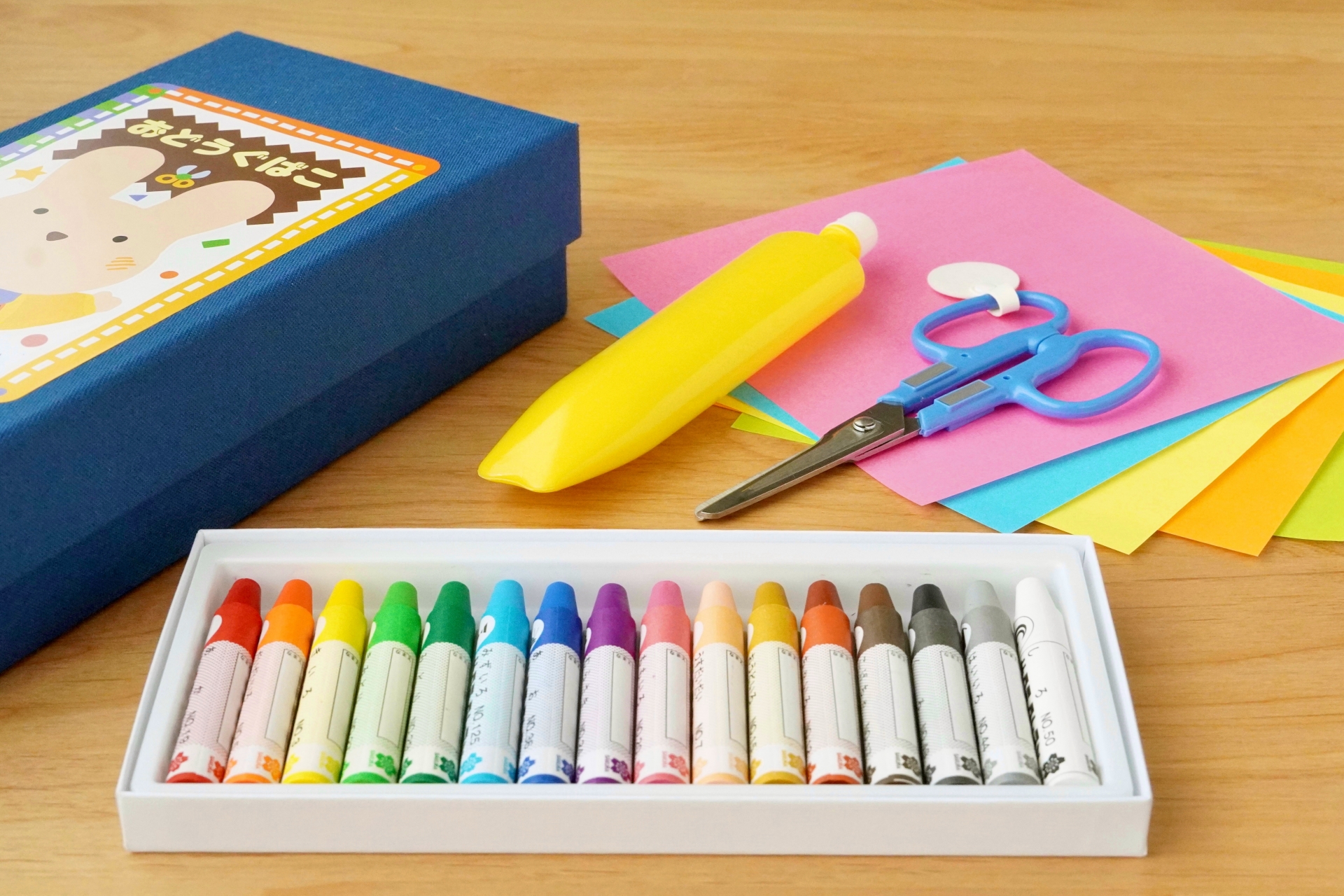 School supply box of crayons, scissors, glue, and color paper