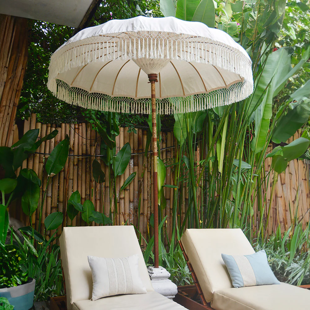 Two sun loungers under decorative white parasol on terrace fenced with bamboo