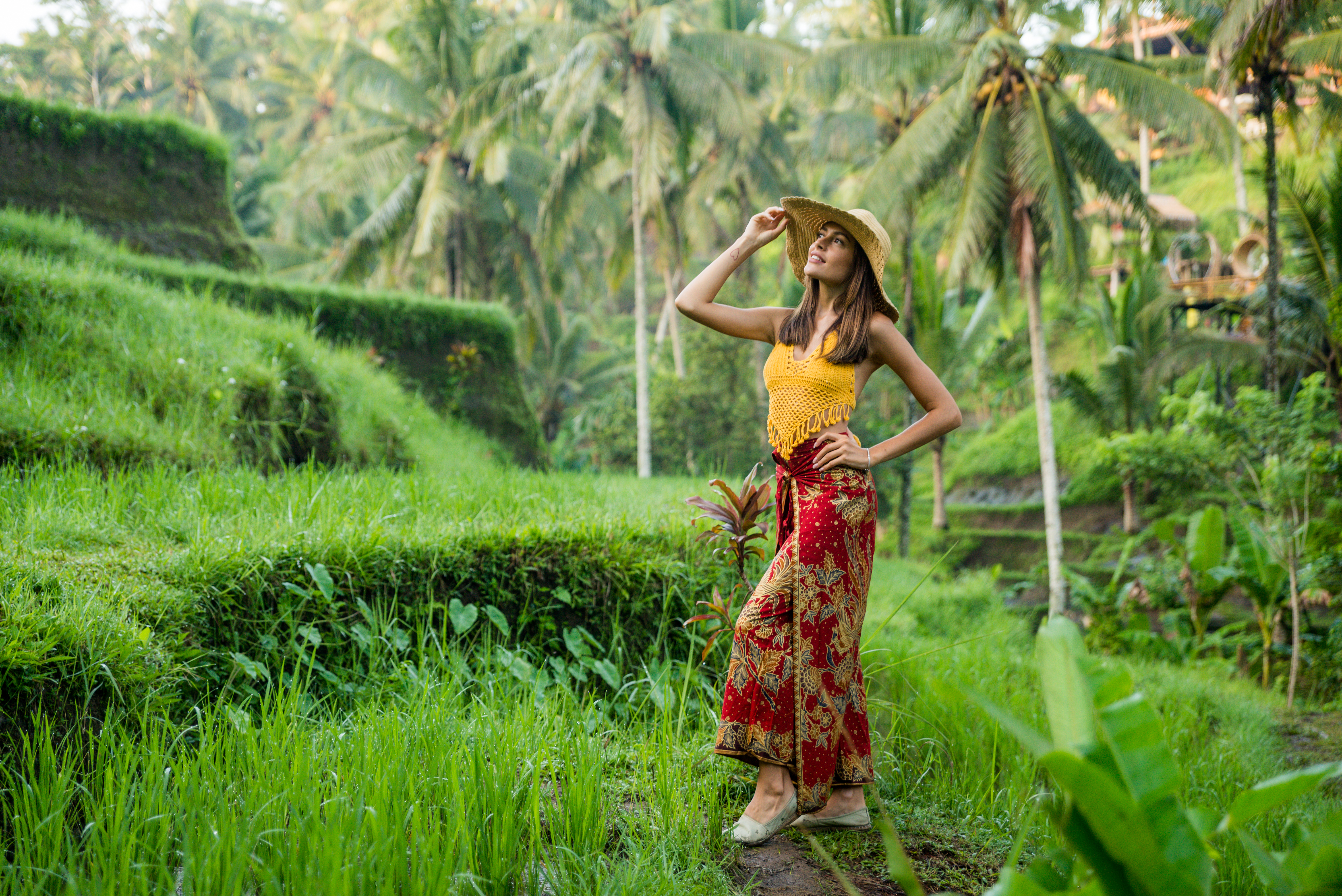 Female tourist in Indonesian batik skirt and straw hat in Bali rice fields